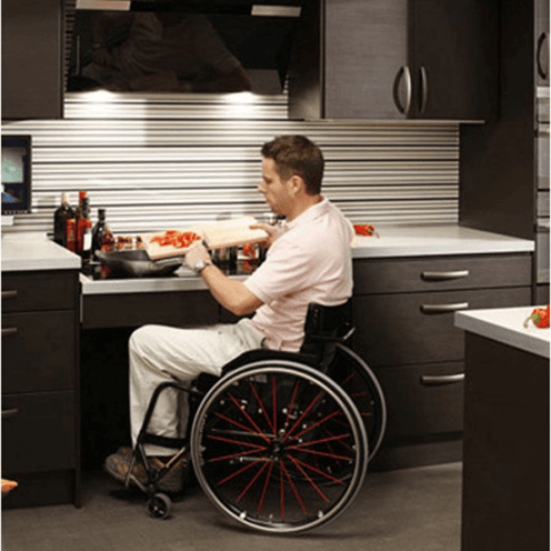 Man in wheelchair using an ADA-compliant induction stovetop