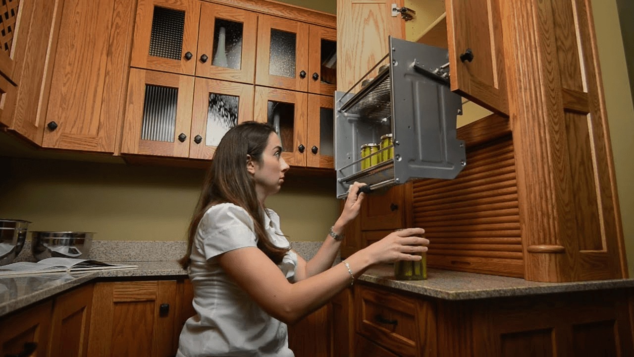 Woman using an ADA-compliant. pull down upper kitchen cabinet