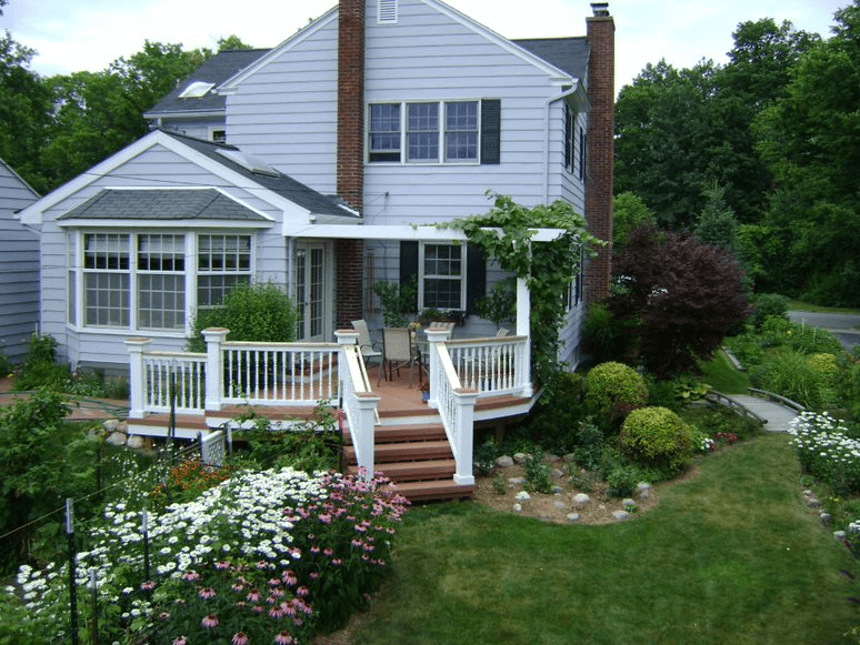 Outdoor deck surrounded by beautiful flowers, bushes, and trees