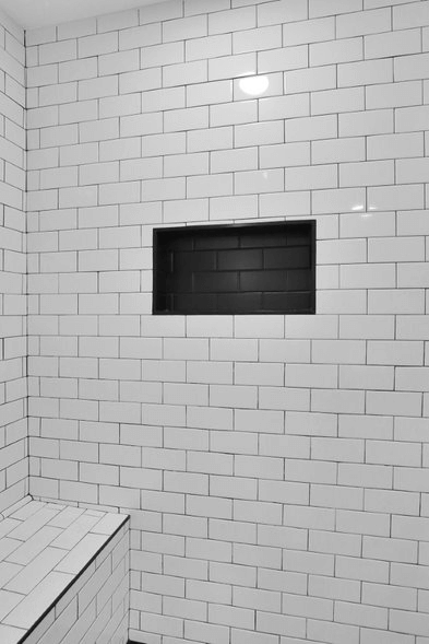 Black tile shower niche contrasting white tile shower