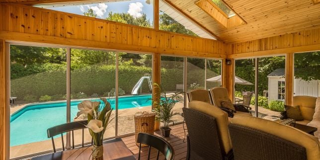 Greater Lansing screened in porch with cedar finish and furniture next to backyard pool