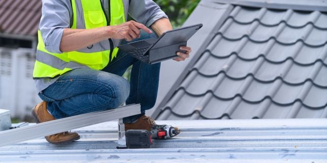 Greater Lansing roofing contractor inspecting roof with tablet