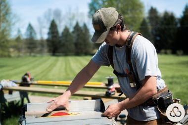 Greater Lansing deck contractor sawing decking board with Custom Built Design and Remodeling