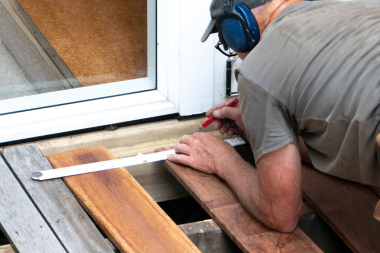 licensed decking contractor measuring deck board in Okemos