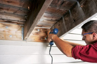 deck remodeler installing ledger board underneath decking space in Lansing
