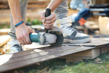 licensed deck contractor sawing decking board in Greater Lansing Area