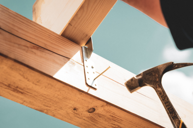 licensed Lansing deck builder hammering nail into decking beam
