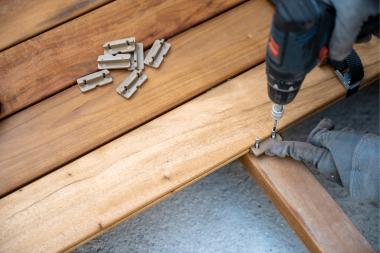 professional Lansing Michigan deck builder drilling nails into wood decking boards