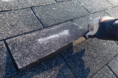 Greater Lansing roofing specialist inspecting shingle