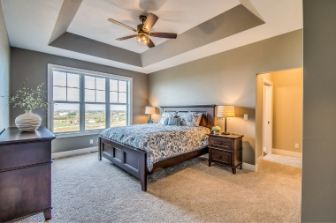 how to design a primary suite addition that feels like a retreat bedroom with large windows and ceiling fan custom built michigan