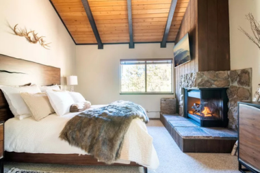 how to design a primary suite addition that feels like a retreat bedroom with fireplace and ceiling beams custom built michigan
