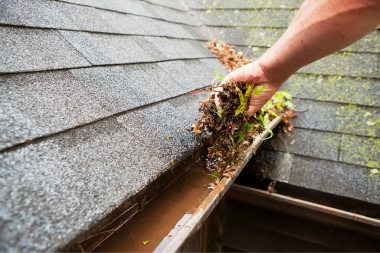 ways you can increase the lifespan of your michigan roof homeowner cleaning debris from gutters custom built mi