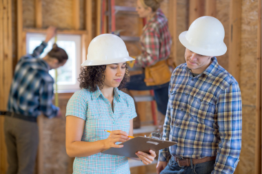 best qualities to look for in a home addition builder contractor and homeowner reviewing remodeling plans custom built michigan