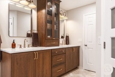 bathroom remodeling project in Williamston Michigan built by Custom Built Design and Remodeling with tall storage cabinet and gold finished fixtures