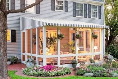 Greater Lansing patio enclosure with hanging garden baskets and striped awning