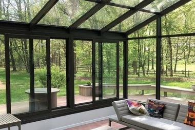 glass patio enclosure sunroom addition in Greater Lansing with black accents and modern furniture