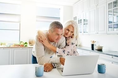 homeowners on laptop in kitchen reviewing Greater Lansing home addition contractors