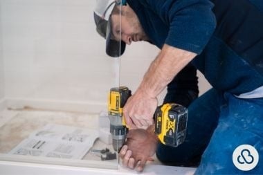 Custom Built home addition contractor installing glass shower frame in project