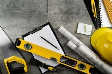 Greater Lansing home addition contractor tools with clipboard and hard hat