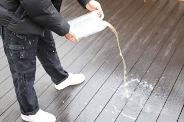 composite deck builder pouring soapy water on decking boards
