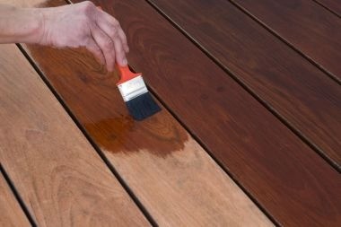 Greater Lansing deck builder using paint brush to stain wood decking boards
