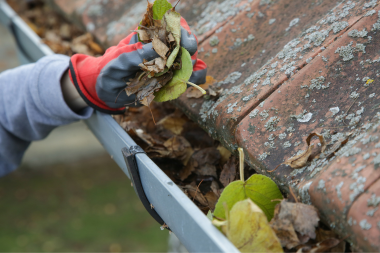 how to address a roof leak if it happens roofing contractor clearing gutters of debris custom built michigan