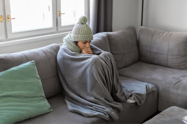 Greater Lansing homeowner under blanket on couch