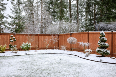 seasonal landscaping tips for year round beauty backyard with snowy foliage and wood fencing custom built michigan