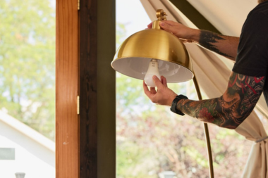 home lighting design tips to brighten shorter fall days contractor installing smart light bulb in pendant fixture custom built michigan