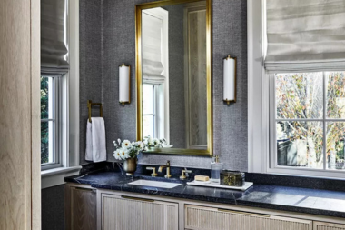 tips for designing a functional guest bathroom sconce lighting fixtures next to gold framed mirror custom built michigan