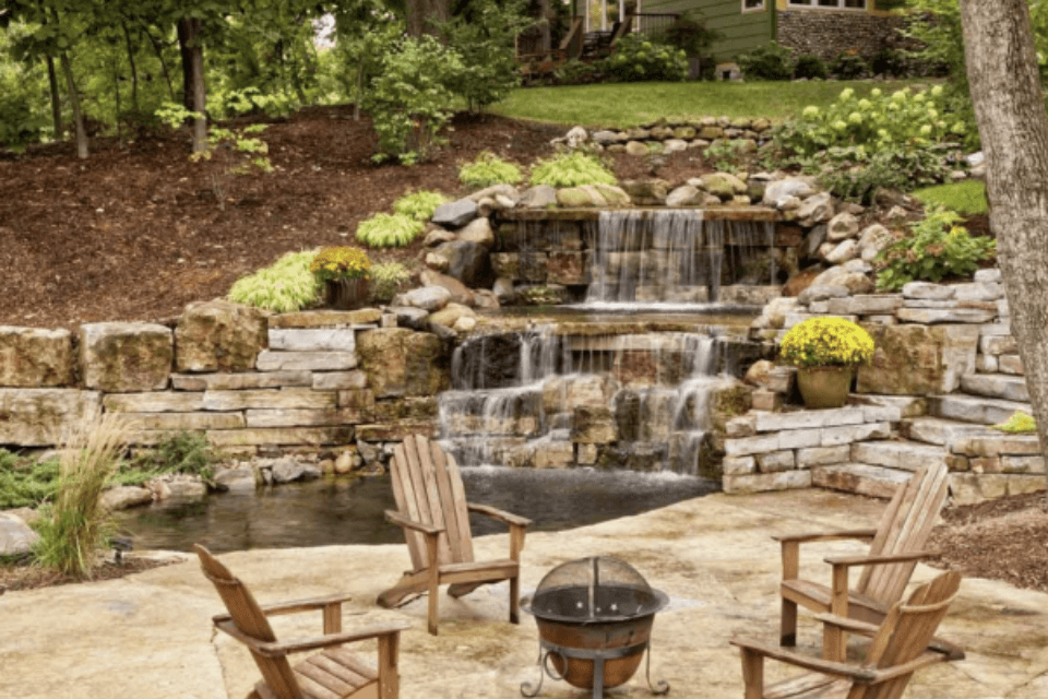 top 5 landscaping companies in Lansing Michigan backyard with waterfall water feature and fire pit