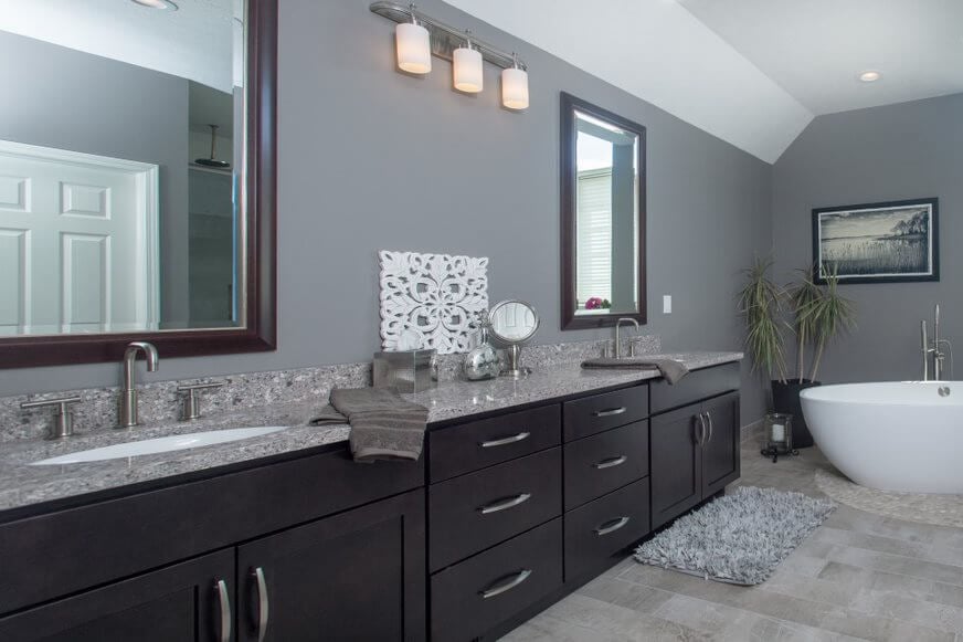 remodeled bathroom with double sink vanity and dark brown cabinets