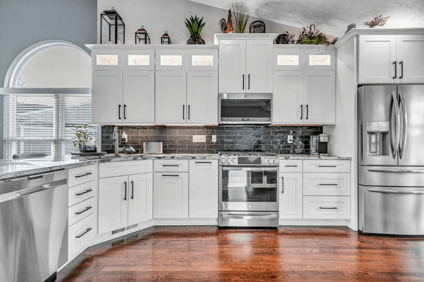 Beautifully remodeled kitchen with wood floors, white cabinets, and black subway tile backsplash