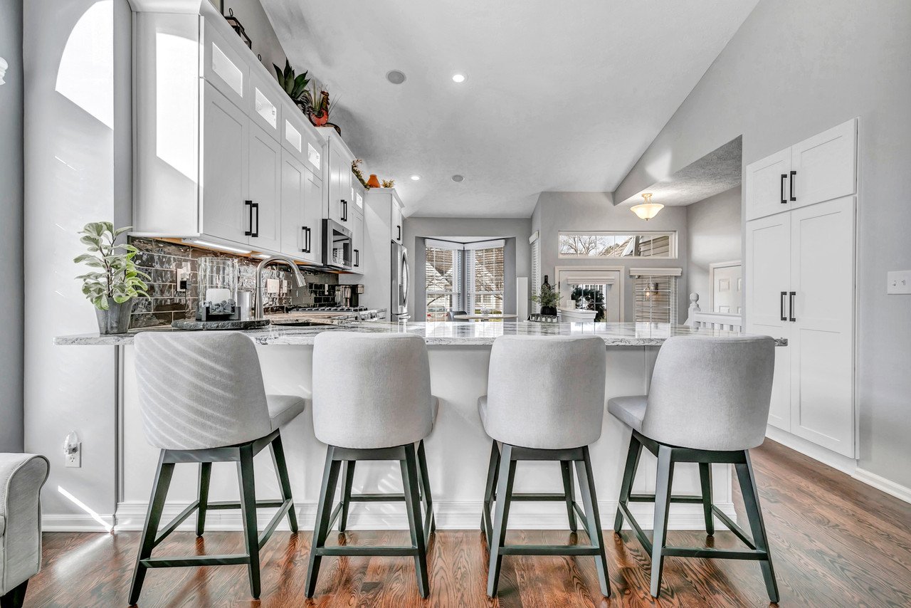 Remodeled kitchen with white cabinets and white breakfast bar seats