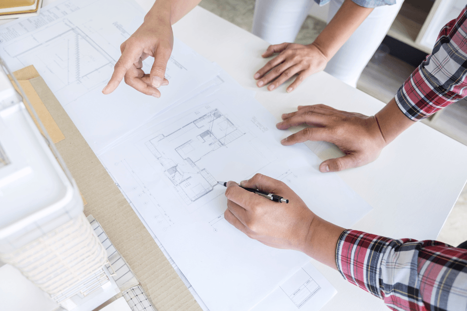 how to navigate hidden remodeling costs with design build contractors remodelers reviewing blueprints custom built michigan