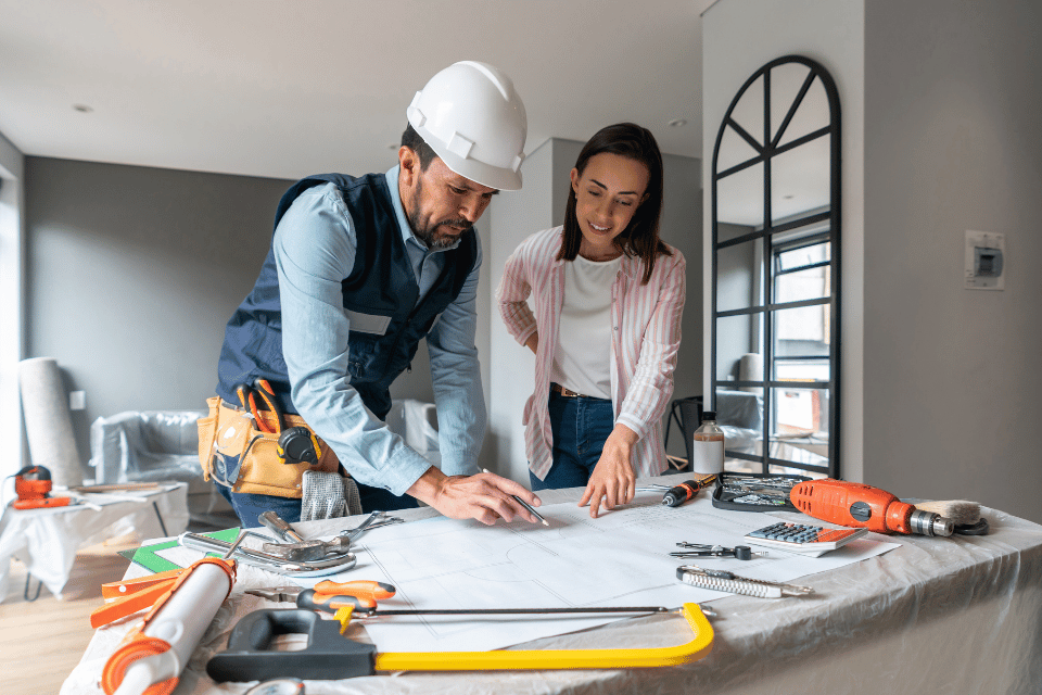 reasons it is challenging to compare remodeling contractor bids upfront remodeler and homeowner reviewing design blueprints custom built michigan