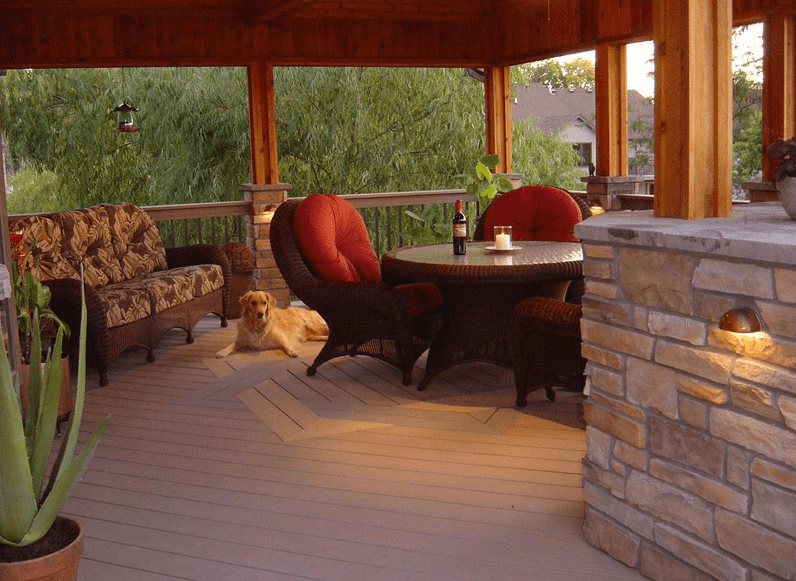 Covered porch with red cushioned chairs, grey couch, and bottle of red wine